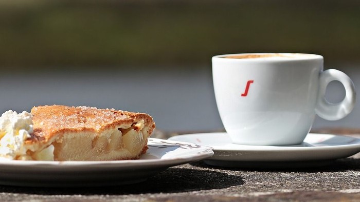 Ein Stück Kuchen und eine Tasse Kaffee auf einem Tisch am Wasser