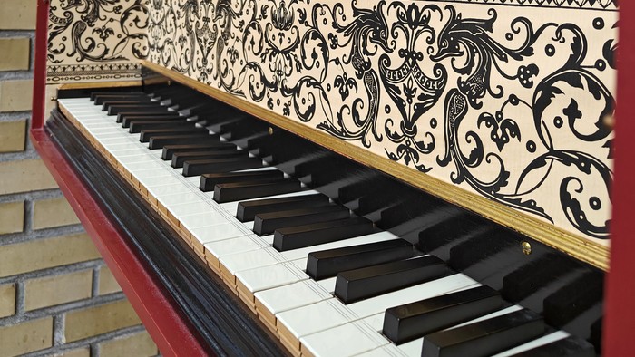 En rød og gul piano med udsmykning og et hvidt ramme på væggen.