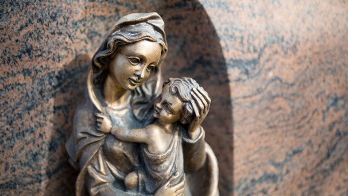 Die Bronzestatue zeigt eine Mutter mit Kind in einer Nische.