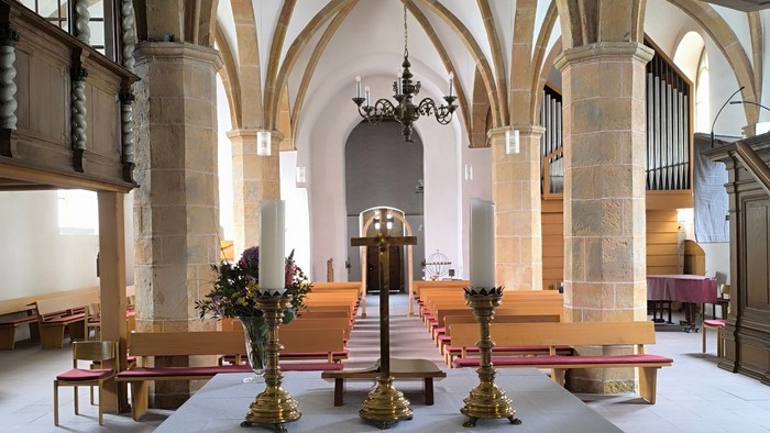 Großer Kircheninnenraum mit hohen Decken, steinernen Säulen und hölzernen Kirchenbänken.