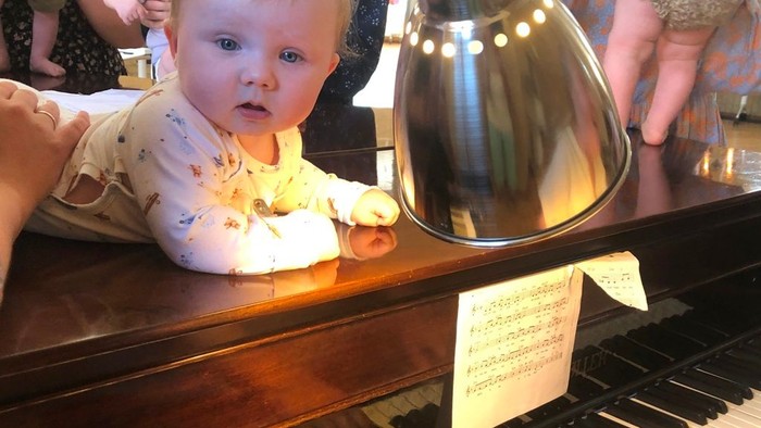 Børn ser i spejl mens en voksende spiller piano