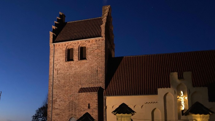 En belysning og juletrær foran kirke