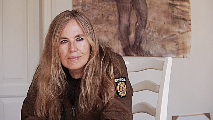 Kvinde, der sidder på en stol foran et maleri.