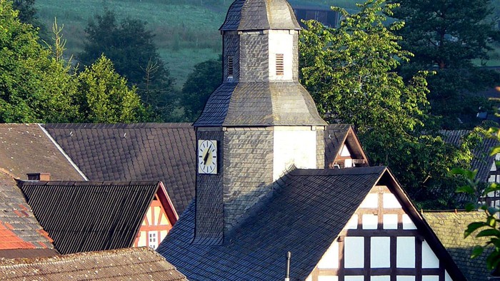 Dorfkirche mit grünem Hügel im Hintergrund