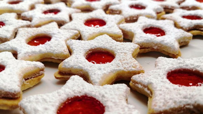 Mehrere Sternförmige Kekse mit Puderzucker und roter Füllung