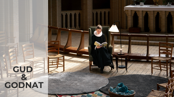 En kvinde i traditionel dutchsk kostume læser i en stue med træmøbler og lysende vinduer