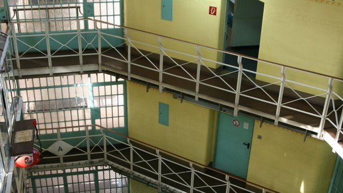 Industrielle Treppe mit Metallgeländern und gelb-grünen Wänden, die mehrere Stockwerke und Sicherheitsausrüstung umfasst.