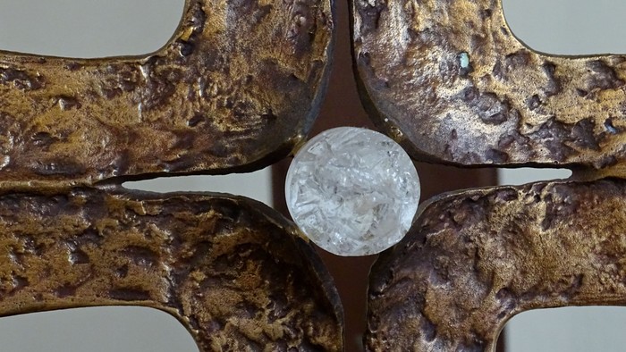 Ein verzierter goldbrauner Metallgegenstand mit einem klaren kugelförmigen Objekt in der Mitte