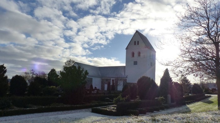En stor, hvid kirke med tårn og en smuk have foran