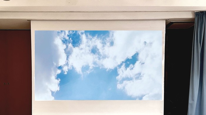 Ein Projektor zeigt ein Bild von Wolken an einer weißen Wand.