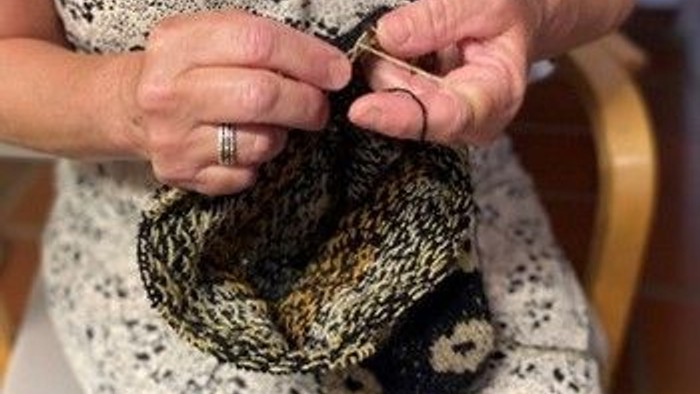 En person sitter og stråler en mørk og lys stråmasket skjorte.