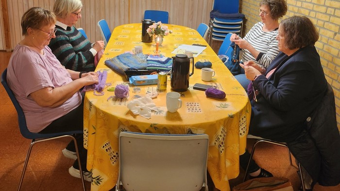 En gruppe mennesker, der sidder rundt om et bord med et gult borddæk.