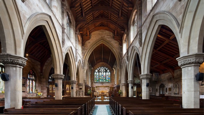 Interior of a large, empty church with wooden pews and arched ceilings.