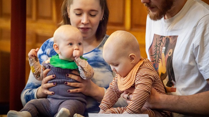 En mor og far sidder med deres to små børn på deres lapper.