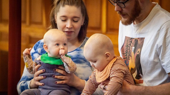 En mor og far sidder med deres to små børn på deres lapper.