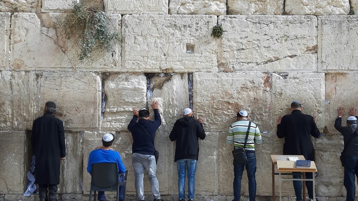 Menschen beten und schreiben an der Klagemauer in Jerusalem, einer bedeutenden religiösen Stätte.
