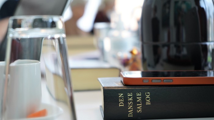 En bord med glas, tæpper, bog og mobiltelefon.