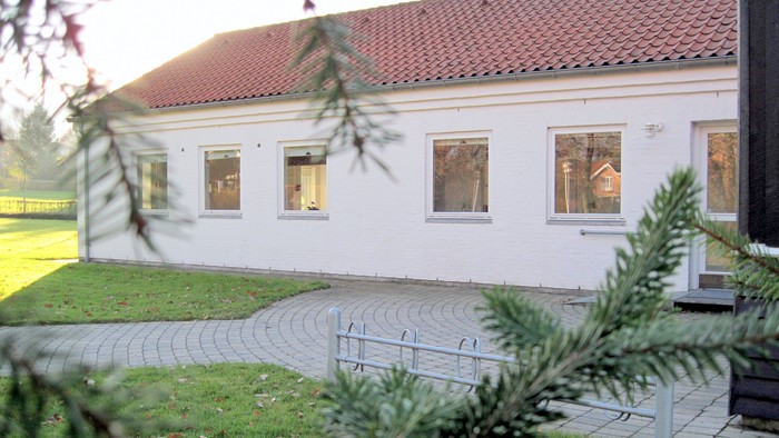 Hus med rødt tag og hvide vinduer.