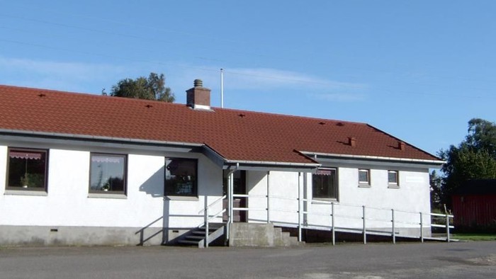 En hvid hytte med rødt tag og en trappe til indgangen.