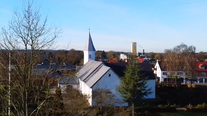 Lille by med kirketårn og omgivende huse.