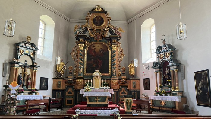 Innenraum einer Kirche mit prächtigem Altar und Kirchenbänken