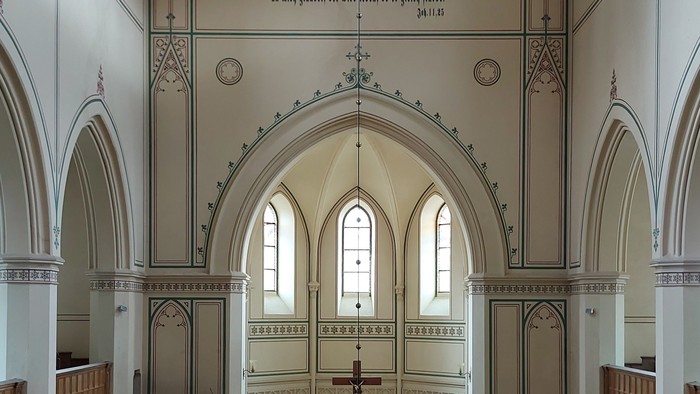 Großzügige Kirche mit hohen Bögen und Stufen zum Altar.