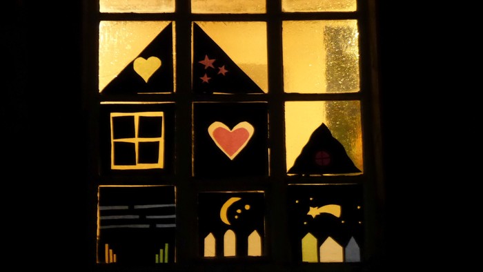 Ein Fenster mit Buntglas, das Herzen, Sterne und einen Mondsichel zeigt.