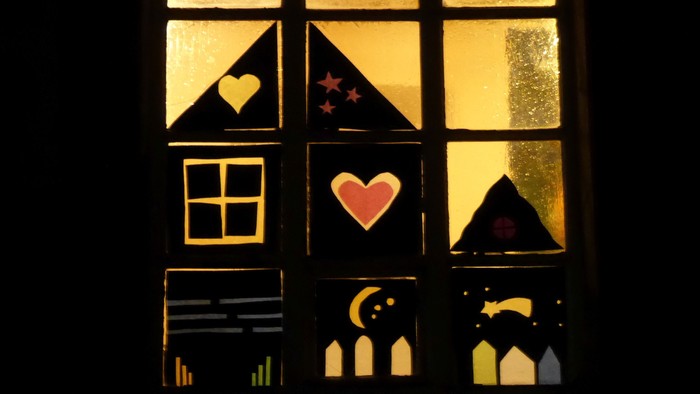 Ein Fenster mit Buntglas, das Herzen, Sterne und einen Mondsichel zeigt.