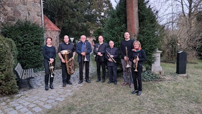 Eine Gruppe von Musikern posiert mit ihren Instrumenten im Freien.