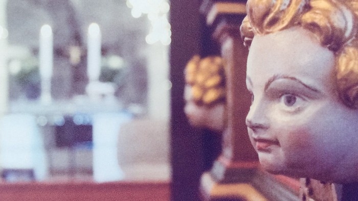 En statue af en ung pige med gyldne hår og kronet hode i en kirke.