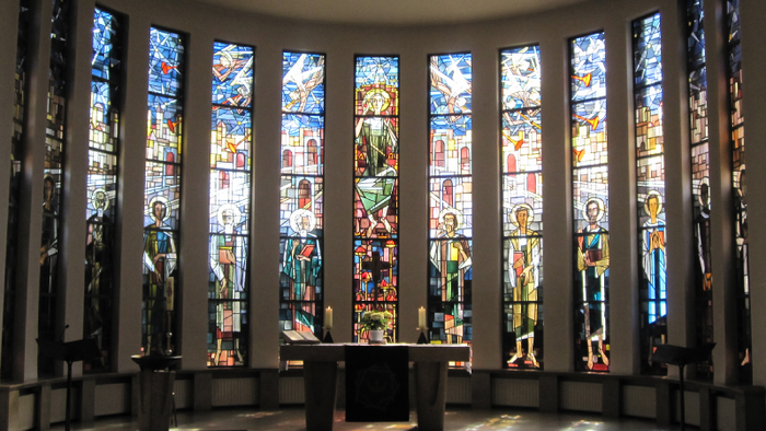 Farbenfrohe Kirchenfenster mit religiösen Motiven erhellen den Innenraum