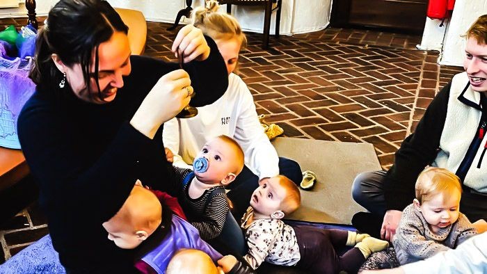 En gruppe af voksne og børn spiller og leker på gulvet.