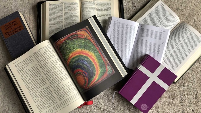 Mehrere aufgeschlagene Bücher liegen auf einem grauen Teppich