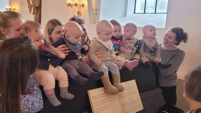 Gruppe af kvinder, der holder babyer, sidder på en sofa