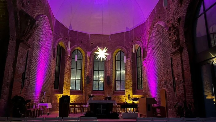 Gekonnte Beleuchtung in historischem Kirchenraum mit hohen Fenstern und Holzbänken