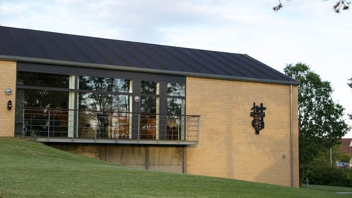 Et moderne hus med store vinduer og træterrasse.