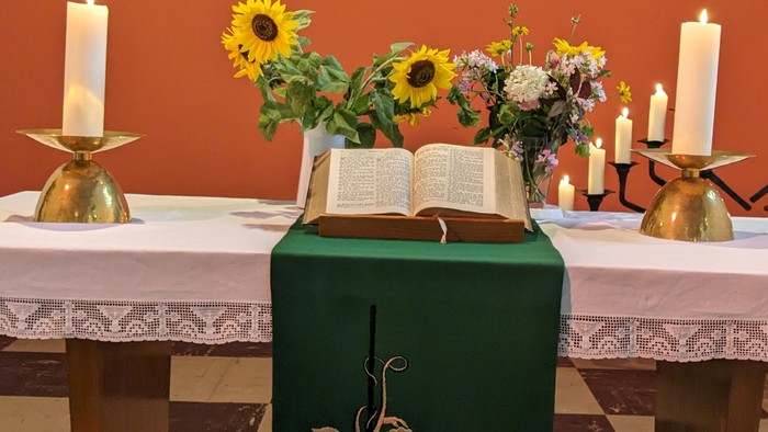 Altar mit Bibel, Kerzen und Sonnenblumen