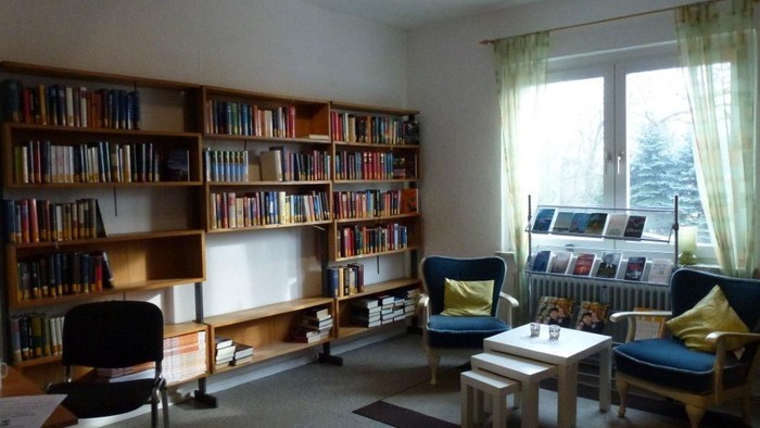 Gemütliches Wohnzimmer mit Bücherregalen, Sesseln und Couchtisch