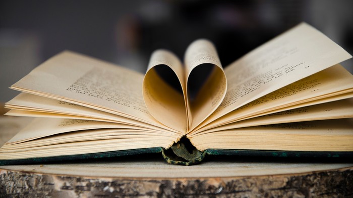 Ein aufgeschlagenes Buch mit herzförmig gefalteten Seiten auf einem Holzboden