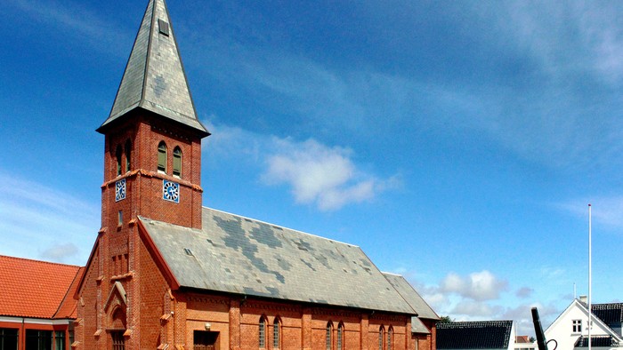 Røde kirke med tårn og klokke.