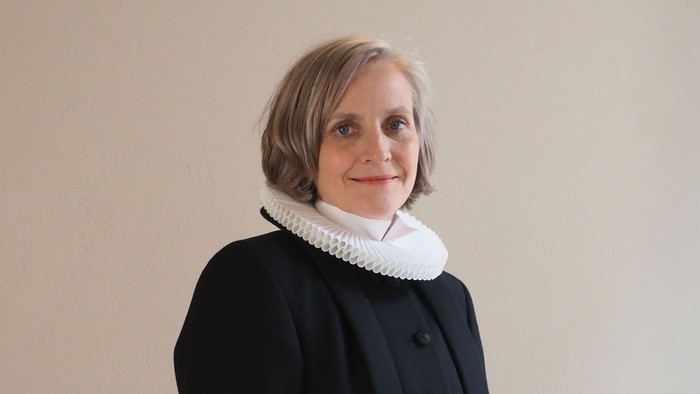 Kvinde i sort kaptajnmø, hvid krage og hvid kuffe.