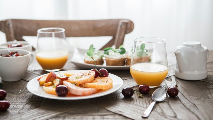 Ein Frühstückstisch mit Obst, Saft und Milch auf einem Holztisch