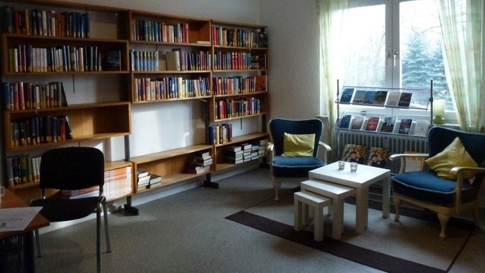 Gemütliches Wohnzimmer mit Bücherregalen, Sesseln und Couchtisch