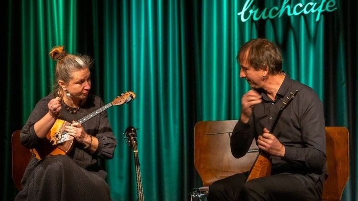 Zwei Musiker, die auf der Bühne Streichinstrumente spielen.