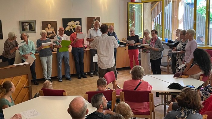 Eine Gruppe von Menschen nimmt an einem Kunstkurs teil, bei dem sie an Zeichentischen stehen und zeichnen.