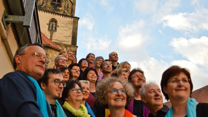 Gruppe von Menschen, die tagsüber vor einem historischen Gebäude mit Türmen posieren.