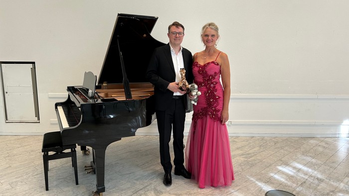 Mand og kvinde poser nær flygel