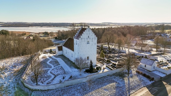 Vinterudsigt fra luften af et historisk hvidt slot omgivet af snedækkede grunde og landskab.