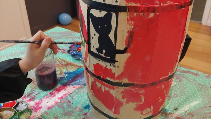 Børn maler en bæger med rød og sort design.