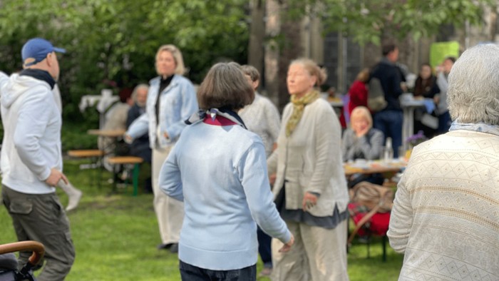 Eine Gruppe älterer Menschen steht im Park und unterhält sich.